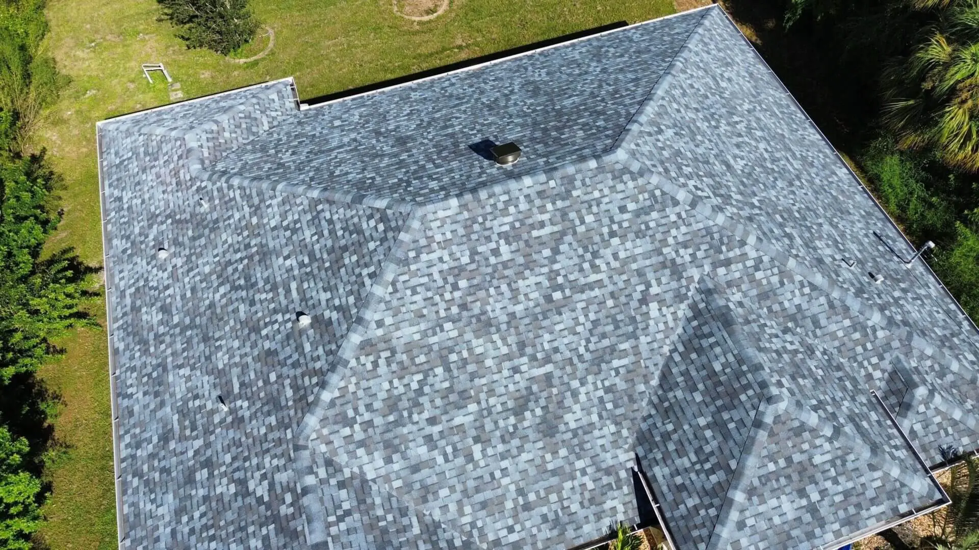 A top view at the roof of a house with trees all around